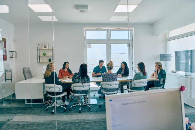 Diverse Business Team Discussing Projects in a Modern Glass Office.